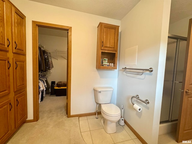 bathroom with a textured ceiling, toilet, an enclosed shower, and tile patterned floors