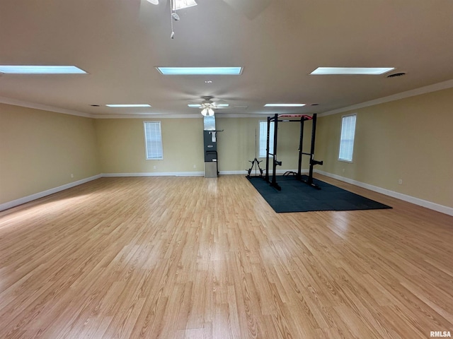 interior space featuring ceiling fan, a skylight, light wood-type flooring, and ornamental molding