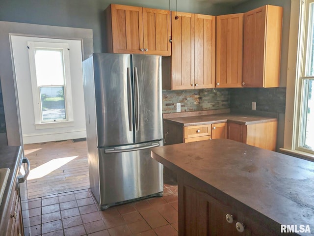 kitchen featuring dark tile patterned flooring, stainless steel refrigerator, and tasteful backsplash