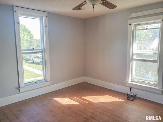 empty room featuring ceiling fan, light wood-type flooring, and a textured ceiling