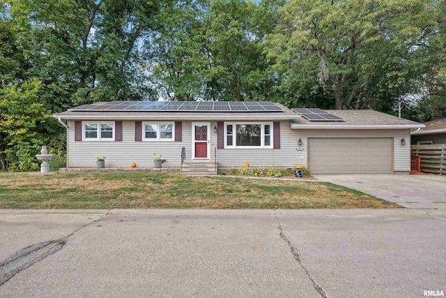 single story home featuring a garage, solar panels, and a front lawn