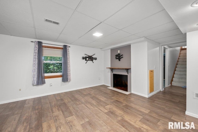 unfurnished living room with hardwood / wood-style flooring and a drop ceiling