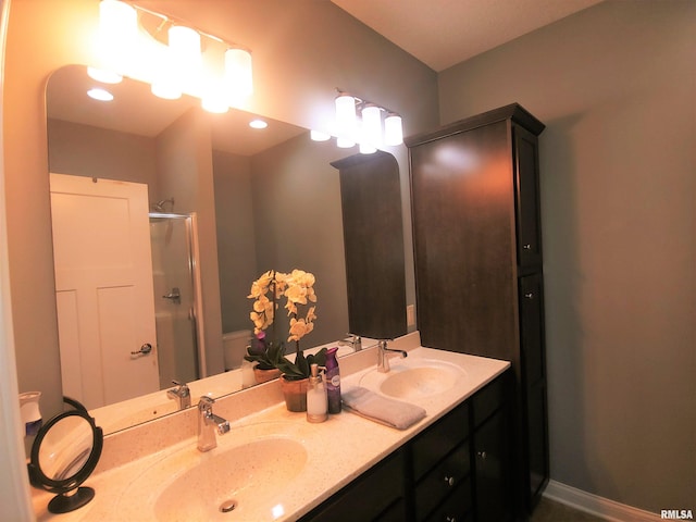 bathroom featuring a shower with door and vanity