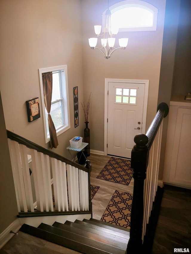 entrance foyer featuring a wealth of natural light, a high ceiling, a chandelier, and dark hardwood / wood-style floors