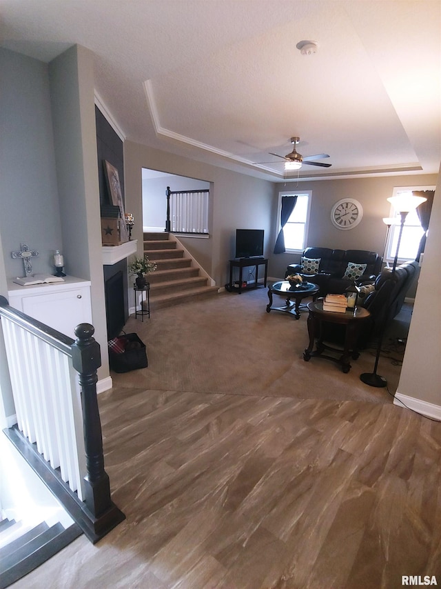 carpeted living room featuring a raised ceiling and ceiling fan