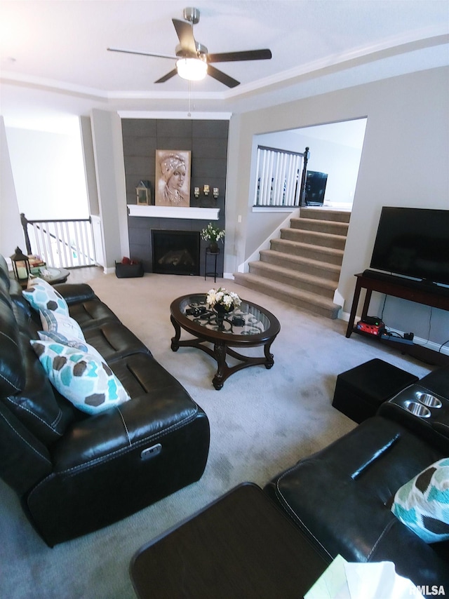 carpeted living room featuring ceiling fan and a large fireplace