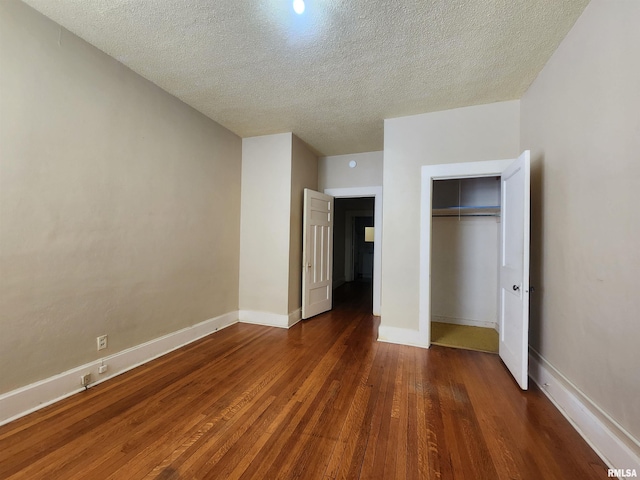 unfurnished bedroom featuring a textured ceiling, dark hardwood / wood-style floors, and a closet