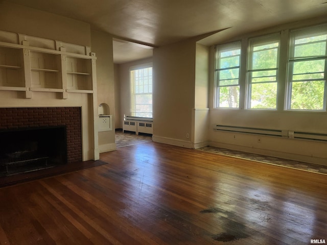 unfurnished living room with dark hardwood / wood-style flooring, a baseboard heating unit, radiator, and a wealth of natural light