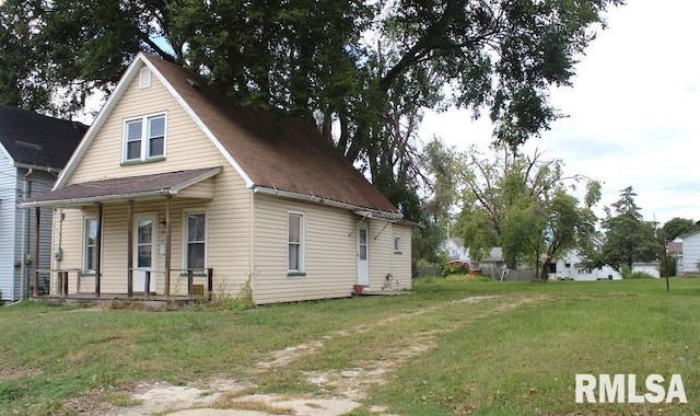 view of side of home with covered porch and a yard