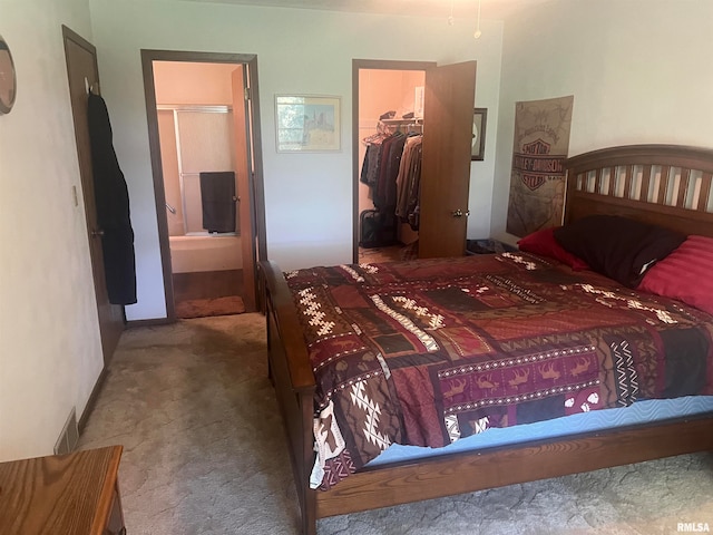 carpeted bedroom with a closet, ensuite bath, and a spacious closet