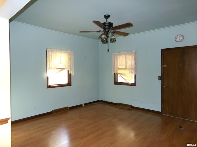 empty room featuring crown molding, hardwood / wood-style floors, and a wealth of natural light