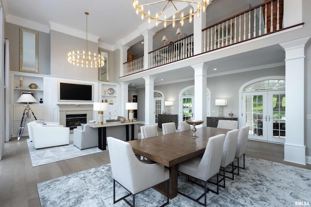 dining space with french doors, ornamental molding, a high ceiling, and wood-type flooring