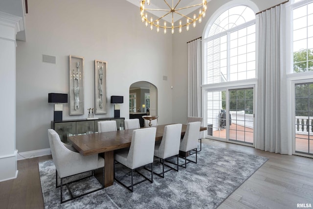 dining space with a towering ceiling, hardwood / wood-style floors, and a chandelier