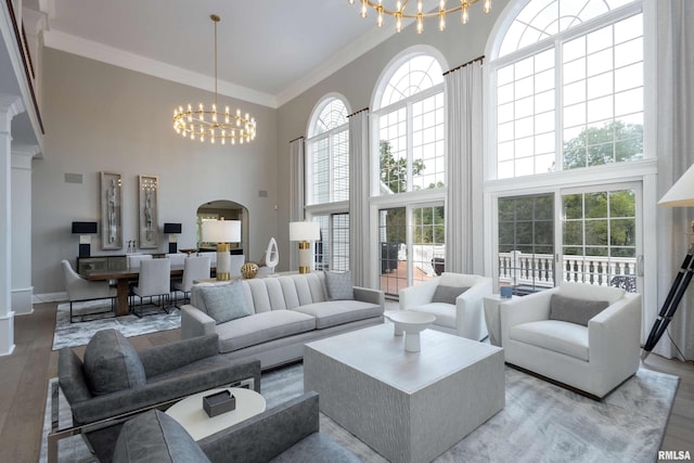 living room with an inviting chandelier, a towering ceiling, light hardwood / wood-style floors, and crown molding