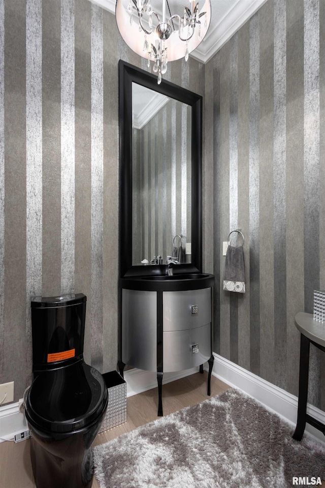 bathroom with wood-type flooring, ornamental molding, vanity, and a notable chandelier