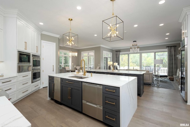 kitchen featuring a wealth of natural light, white cabinetry, an island with sink, and decorative light fixtures