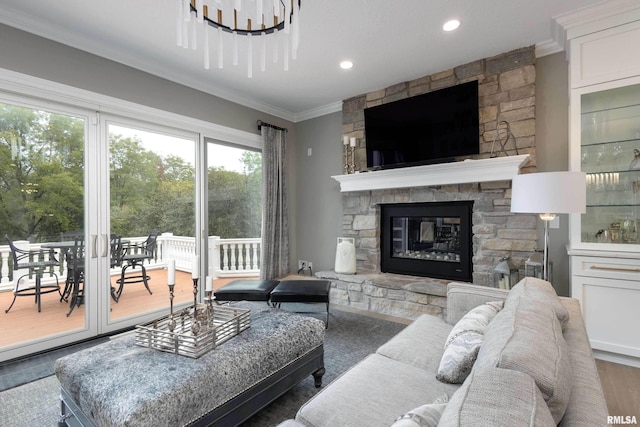 living room with crown molding, a stone fireplace, an inviting chandelier, and dark wood-type flooring