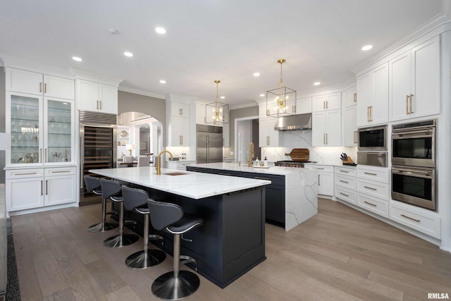 kitchen featuring pendant lighting, sink, white cabinetry, built in appliances, and a spacious island