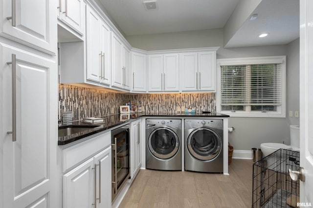 clothes washing area with beverage cooler, light hardwood / wood-style floors, and separate washer and dryer