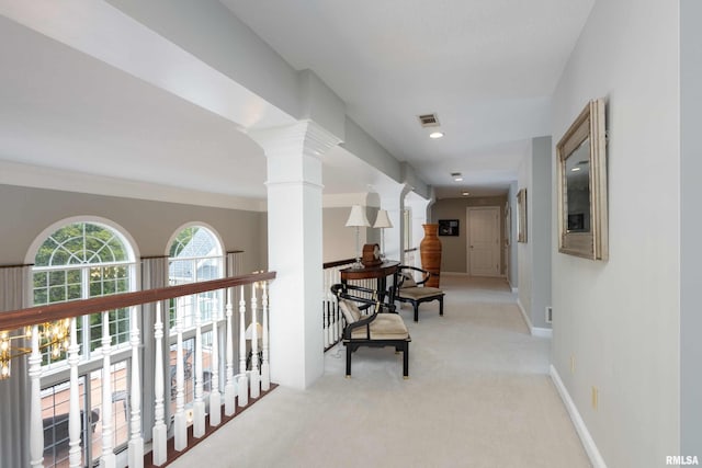 hallway featuring a notable chandelier, light carpet, and ornate columns