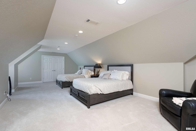 bedroom featuring vaulted ceiling, a closet, light colored carpet, and a textured ceiling