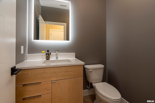 bathroom with vanity, toilet, and hardwood / wood-style flooring