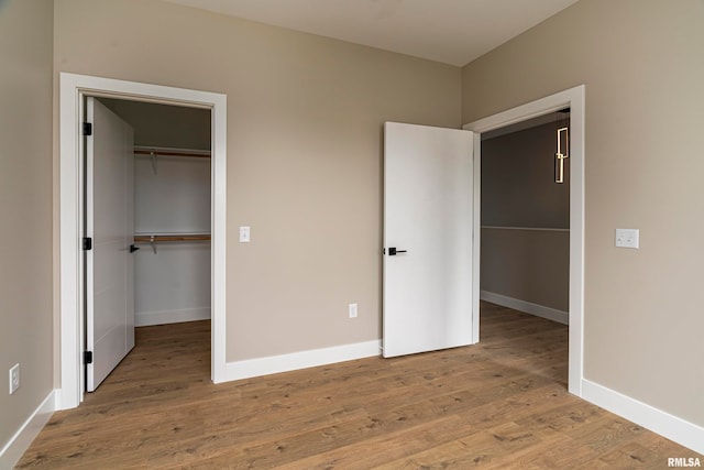 unfurnished bedroom featuring a walk in closet, a closet, and hardwood / wood-style flooring