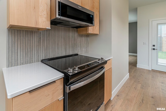 kitchen with light brown cabinetry, stainless steel appliances, and light wood-type flooring