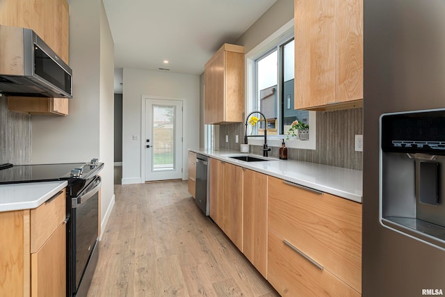 kitchen featuring appliances with stainless steel finishes, light wood-type flooring, sink, and a wealth of natural light