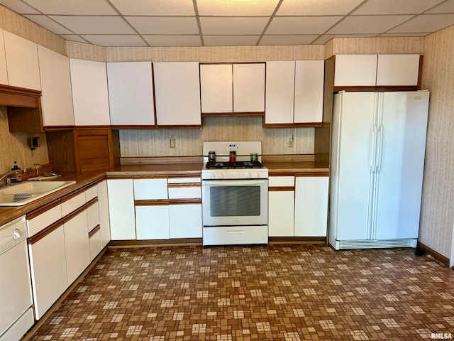 kitchen with a paneled ceiling, sink, white appliances, and white cabinetry