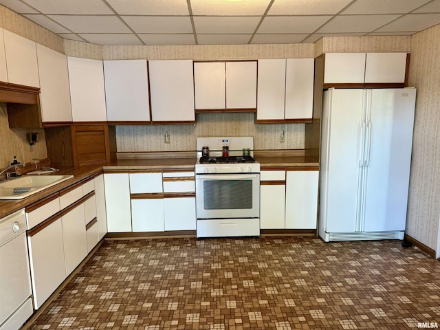 kitchen featuring a sink, white appliances, and a paneled ceiling