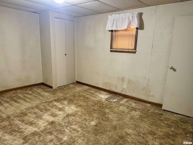 basement with carpet floors, baseboards, and a drop ceiling