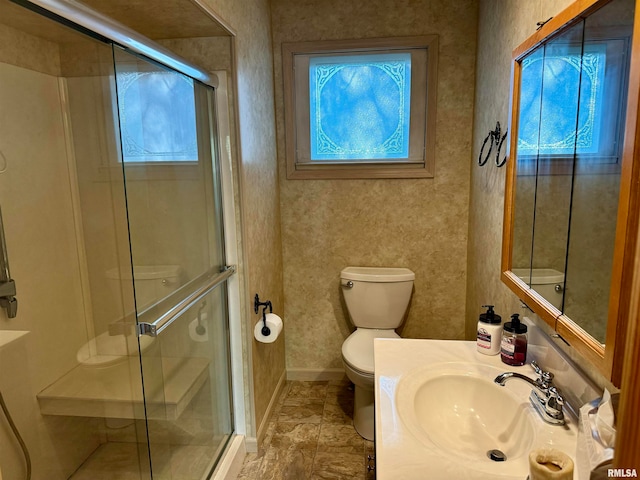 bathroom featuring a shower with door, toilet, vanity, and a wealth of natural light