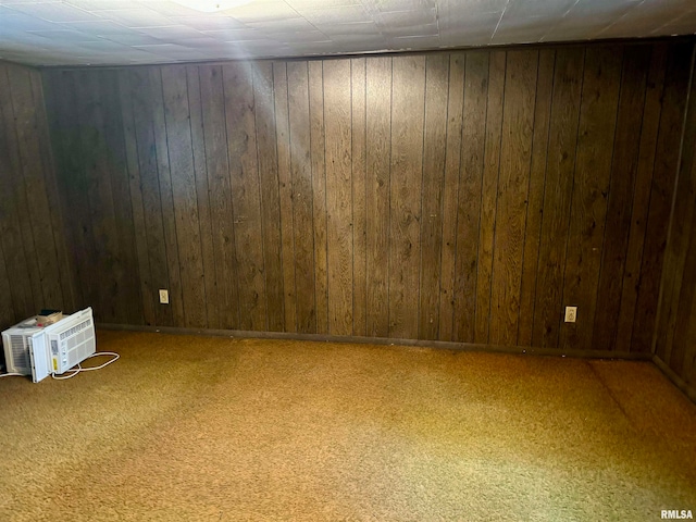 carpeted empty room featuring wooden walls and an AC wall unit