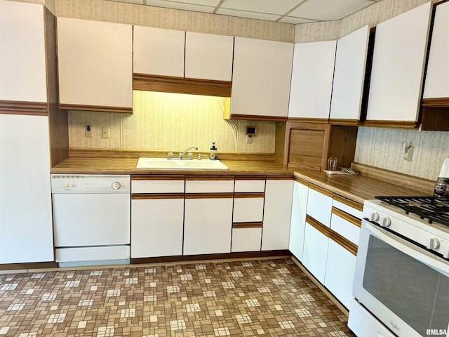 kitchen with a sink, white cabinets, and white appliances
