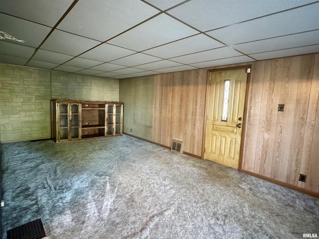 interior space featuring visible vents, wood walls, a paneled ceiling, and carpet
