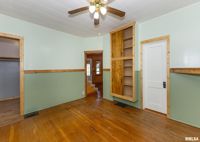 unfurnished bedroom with ornamental molding, ceiling fan, and hardwood / wood-style flooring