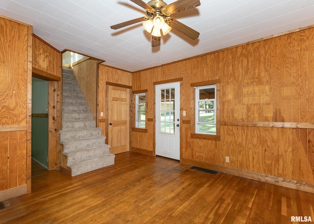 entryway featuring wooden walls, wood-type flooring, and ceiling fan