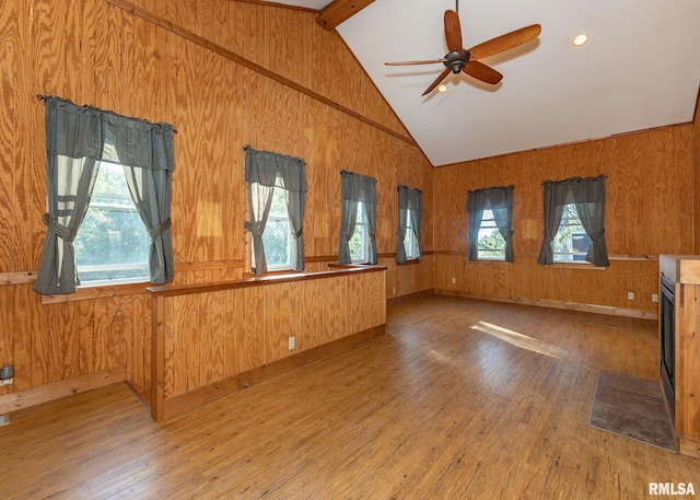 unfurnished living room featuring vaulted ceiling with beams, wood-type flooring, and wood walls