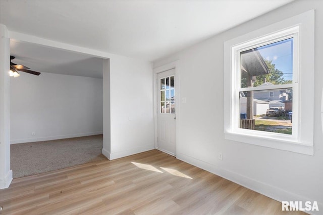 empty room with ceiling fan and light hardwood / wood-style flooring