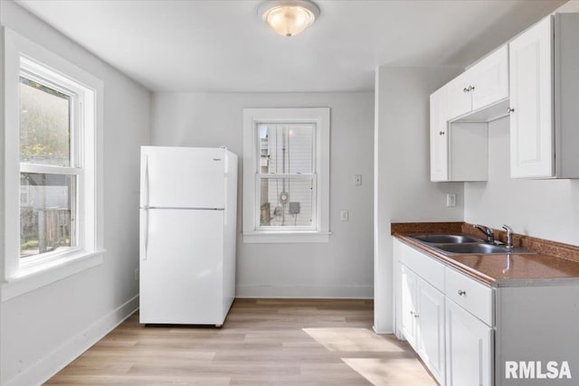 kitchen with white cabinets, sink, light hardwood / wood-style flooring, and white refrigerator