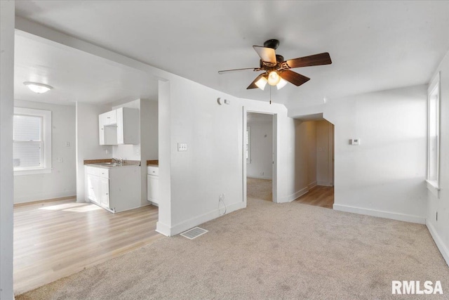 unfurnished living room featuring light hardwood / wood-style floors, ceiling fan, and sink