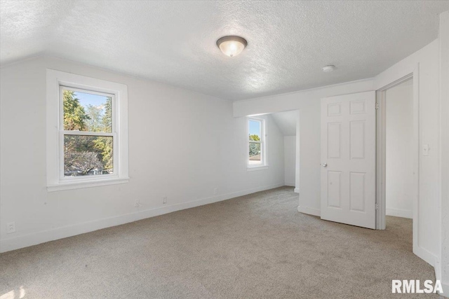 unfurnished bedroom featuring vaulted ceiling, multiple windows, and a textured ceiling