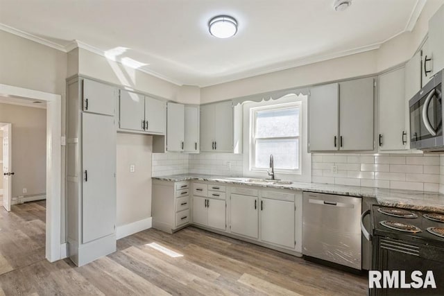 kitchen with a baseboard heating unit, light wood-type flooring, sink, stainless steel appliances, and light stone countertops