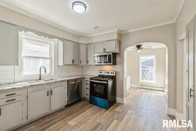 kitchen featuring a healthy amount of sunlight, backsplash, stainless steel appliances, and a baseboard radiator