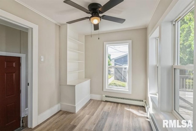 interior space featuring crown molding, a baseboard heating unit, ceiling fan, and light hardwood / wood-style flooring