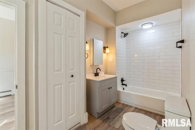 full bathroom featuring vanity, toilet, tiled shower / bath combo, a baseboard heating unit, and hardwood / wood-style floors