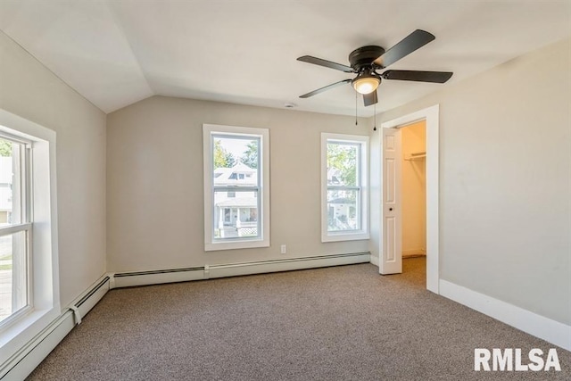 interior space featuring light colored carpet, a baseboard radiator, lofted ceiling, and a walk in closet