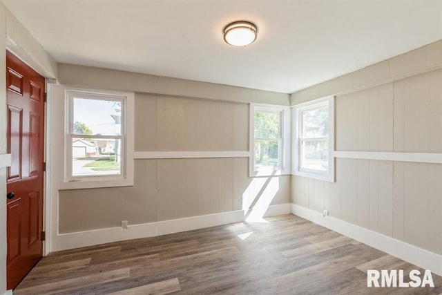 unfurnished room with a healthy amount of sunlight, wood-type flooring, and wood walls