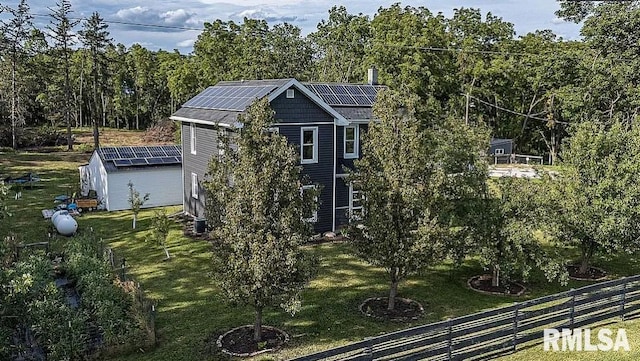 view of home's exterior with an outdoor structure, fence, a lawn, and roof mounted solar panels